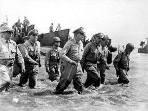 Accompanied by General MacArthur is Philippine President Sergio Osmena and other US and Philippines Generals.