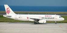 An aircraft painted in white, with a red dragon on its tail and the name Dragonair in both English and Traditional Chinese on the fuselage, taxiing on the taxiway