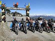 Six motorcyclists at a war memorial in the mountains