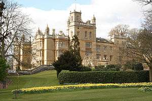 A mansion surrounded by trees and hedges.