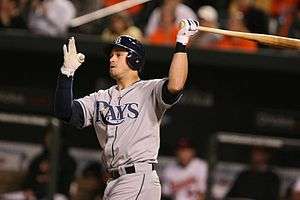 A right-handed man in a grey baseball uniform reading "Rays" swings a baseball bat.