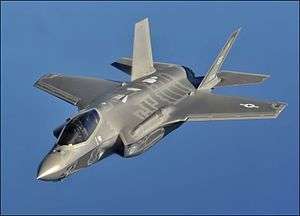 Gray fighter aircraft flying against a backdrop of clouds.