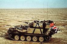 small armoured vehicle alone in the desert. The flag of the United Kingdom can just be seen on the rear