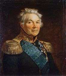 Painting shows a gray-haired man with a round face wearing a very dark military coat with gold epaulettes, a gold collar and a blue velvet sash over his shoulder.