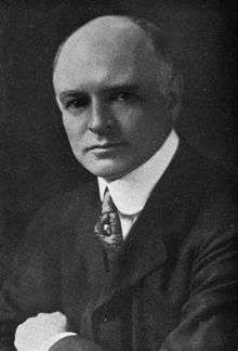 Black and white photograph of a middle-aged man in a dark suit and white shirt