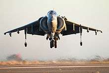 Front-view of gray jet aircraft executing a hover. The huge engine inlets are on both sides of the fuselage