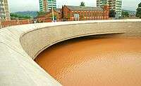 Concrete underpass filled to the roof with brown water.