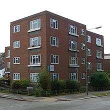 Three-quarter view of a four-storey red-brick block of flats on a corner site.  One section projects, and two other parts are mostly hidden to the left and right.  A sign reads "Florence Court".