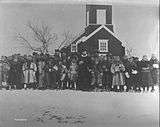 Black and white photograph of a wooden church building with a crowd of people in front of it