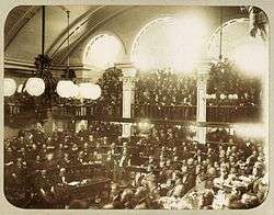 Looking down on assembled legislators on the floor of the hall with observers crowding an arcaded balcony.