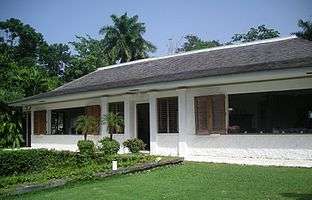 A white-washed bungalow with a lawn in front