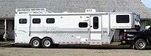 A large white trailer with the back end of a black pickup truck visible