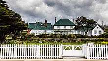 Large, rambling house with greenhouse and white fence