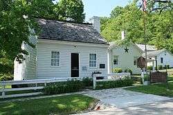  White clapboard house and outbuildings behind a white fence