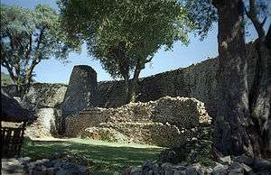 A picture of a semi-spherically shaped stone enclosure sitting in front of a larger wall.