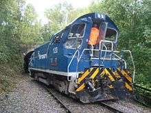 Diesel shunting locomotive in blue livery, displaced at an angle across the railway tracks, with damage visible at the rear