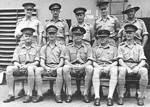 Formal group portrait of men in Army uniforms. One is wearing a slouch hat; the rest have peaked caps