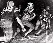 Black and white image of Cannon during his punt return against Ole Miss, running between several defenders