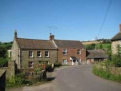 Two storey stone houses with a road in front.