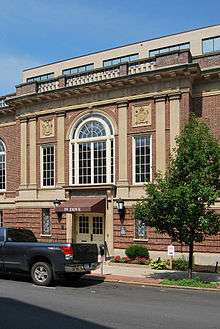 A section of the front of the building with the ornate main entrance. Above it is a large window with a semicircular upper portion. Carved into the stone above it are the words "Harmanus Bleecker Library"