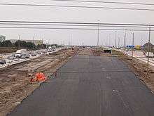 "A paved segment of highway next to a busy freeway."