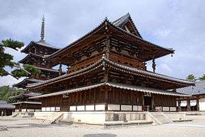 A two-storied wooden gate and a pagoda in the background.