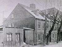 Black and white image of wooden house in an urban district.