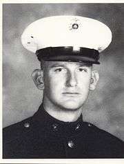 A black-and-white photo of a young white man in his military dress uniform with hat