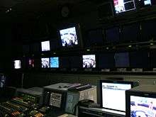 TV director's console, with many monitors on wall