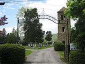 An image of the memorial located atop a small mound in a cemetery