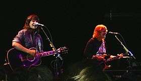 Indigo Girls strumming guitars onstage