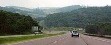 A four-lane highway descending a hill, with more hills visible in the background.