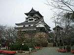 A castle with white walls and dark roofs on a base of unhewn stones.