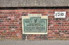 Green plaque mounted on a brick wall