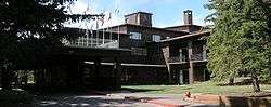 alt=Photograph of the Jackson Lake Lodge, a modern structure with many horizontal lines among the vertical trees of Grand Teton National Park.