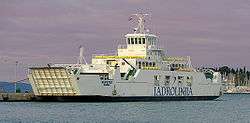 White ferry with ramps in the up-position, moored at jetty