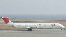 A McDonnell Douglas MD-81 aircraft  taxiing on the tarmac, with a grey looking seaview on the background