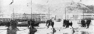 Five submarines moored next to each other with men standing on them