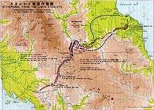 A map with Japanese and English characters on it, depicting the withdrawal of Japanese forces north over the Owen Stanley Range along the Kokoda Track. The route of the Japanese withdrawal is shown in black dotted arrows, while the advance of the Australian forces that followed them up is shown in red