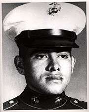 A black and white headshot of Jiminez wearing his military dress blue uniform with hat. He is looking slightly to the right.