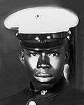 A black-and-white photo of a black man wearing his dress blue Marine Corps uniform with hat