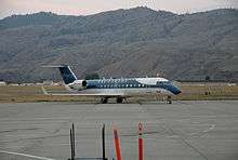 An aircraft located on a runway, with a mountain in the background.