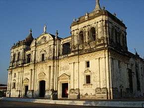 Main facade of a large church with two massive and low and three main doors.