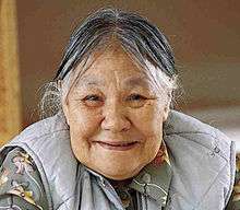 "A colour picture of a smiling Kenojuak Ashevak in 1997 while at work in the print shop."