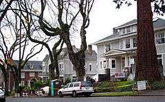 Photograph of three houses along one side of a street.