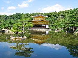 A three storied pavilion. The lower story is in wood and white color, the two upper stories golden.