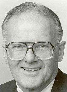 Posed head-shot photograph of Hunt wearing large metal-framed eyeglasses and smiling