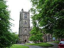 The west part of a church with tall windows and a tall four-stage tower.