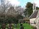 Masonry remains of corner of caste, surrounded by trees, on a bank overlooking a churchyard