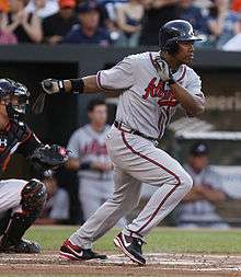 A baseball player wearing a uniform inscribed with the word "Atlanta" has swung a baseball bat and is running. The catcher is partially visible.